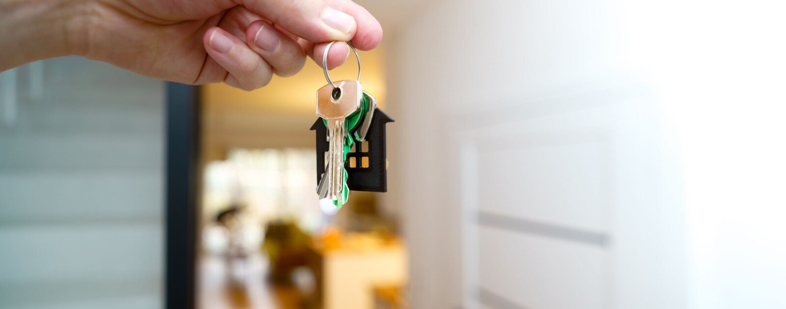 Main tenant des clés devant la porte d’un appartement