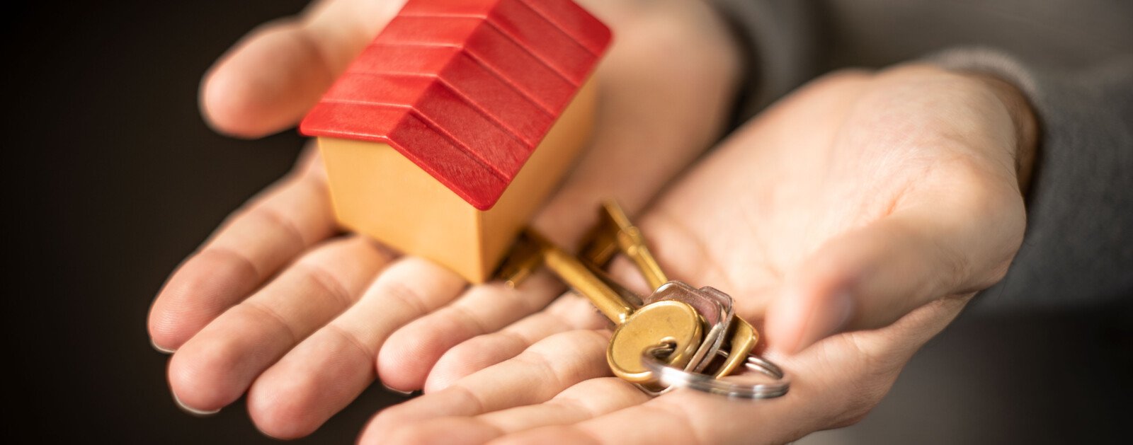 Maison miniature et clés dans des mains, illustration de la gestion locative