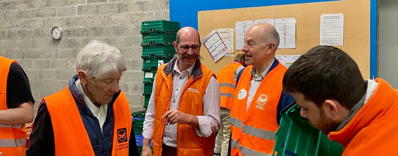 Bénévoles de la Banque alimentaire de Loire-Atlantique en gilets orange triant des légumes dans un entrepôt ; photographie d’archives.