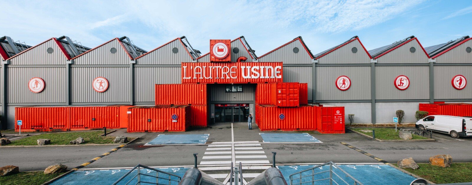 Façade du complexe L'Autre Usine à Cholet, entrée sous l'enseigne rouge, photographie d'archive de 2025