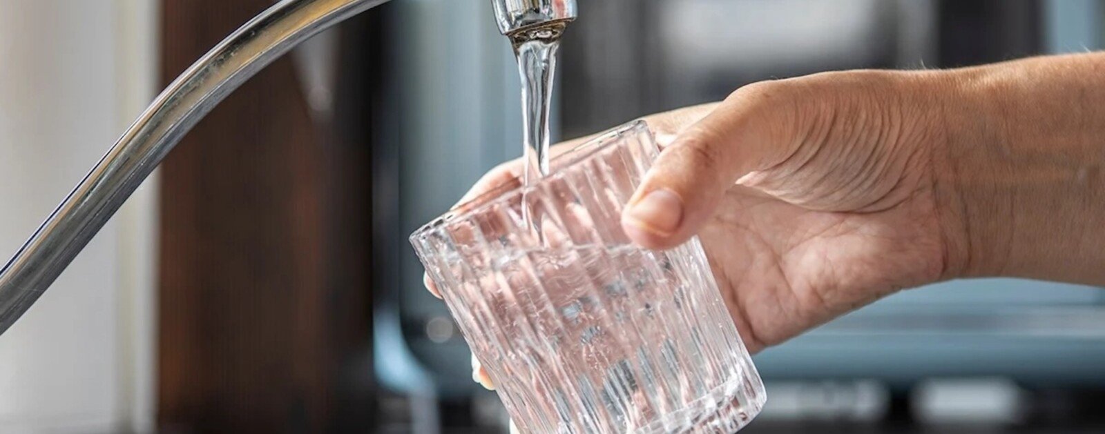 Verre rempli sous un robinet pour illustrer la qualité de l’eau potable