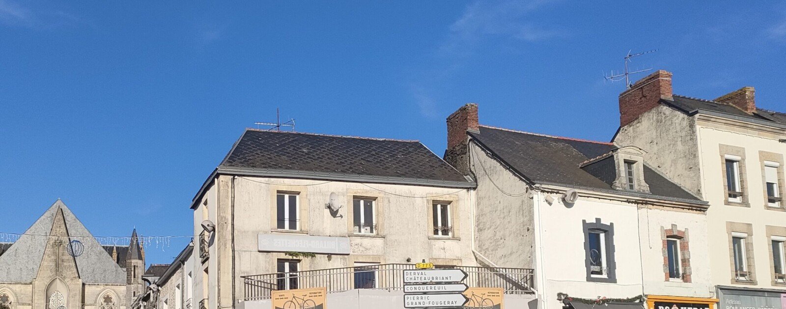 Commerces et bâtiments anciens à l'angle de la place Simon et de la rue de l'Église à Guémené-Penfao