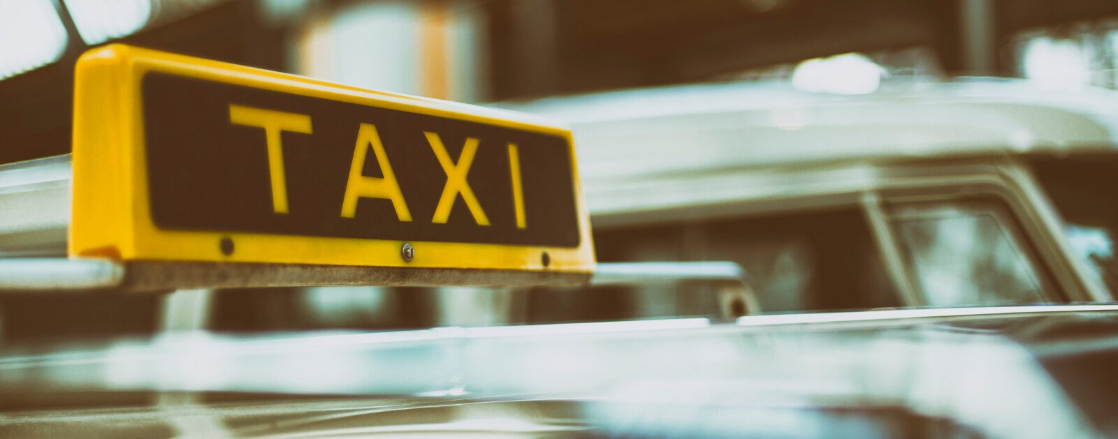 Enseigne jaune TAXI photographiée sur le toit d'une voiture, illustration du transport de patients