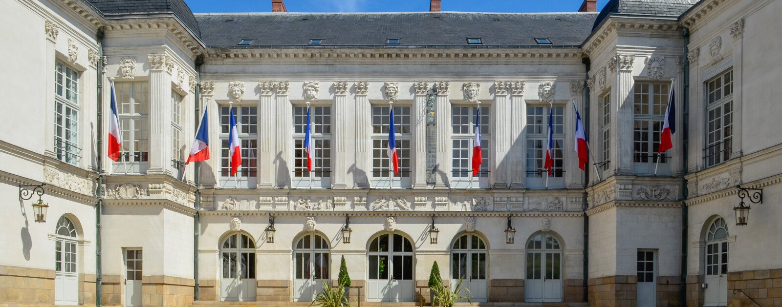 Cour intérieure et façade de l'hôtel de ville de Nantes avec des drapeaux français