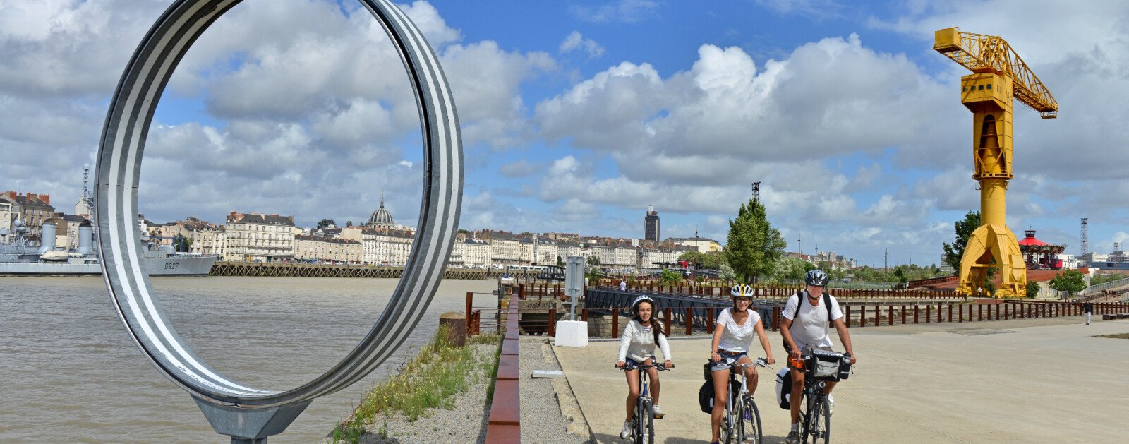 Trois cyclistes circulent le long de la Loire, quai des Antilles à Nantes