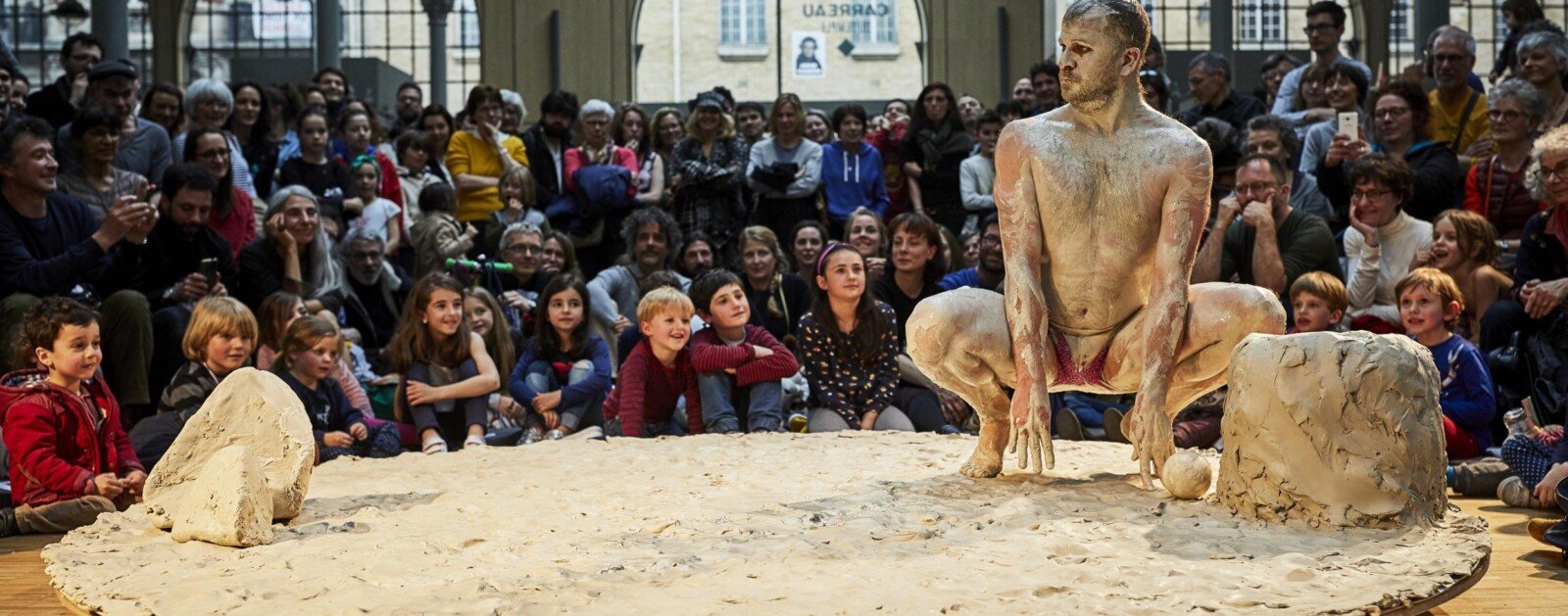 Artiste du spectacle Gadoue sur une scène recouverte d'argile devant des spectateurs
